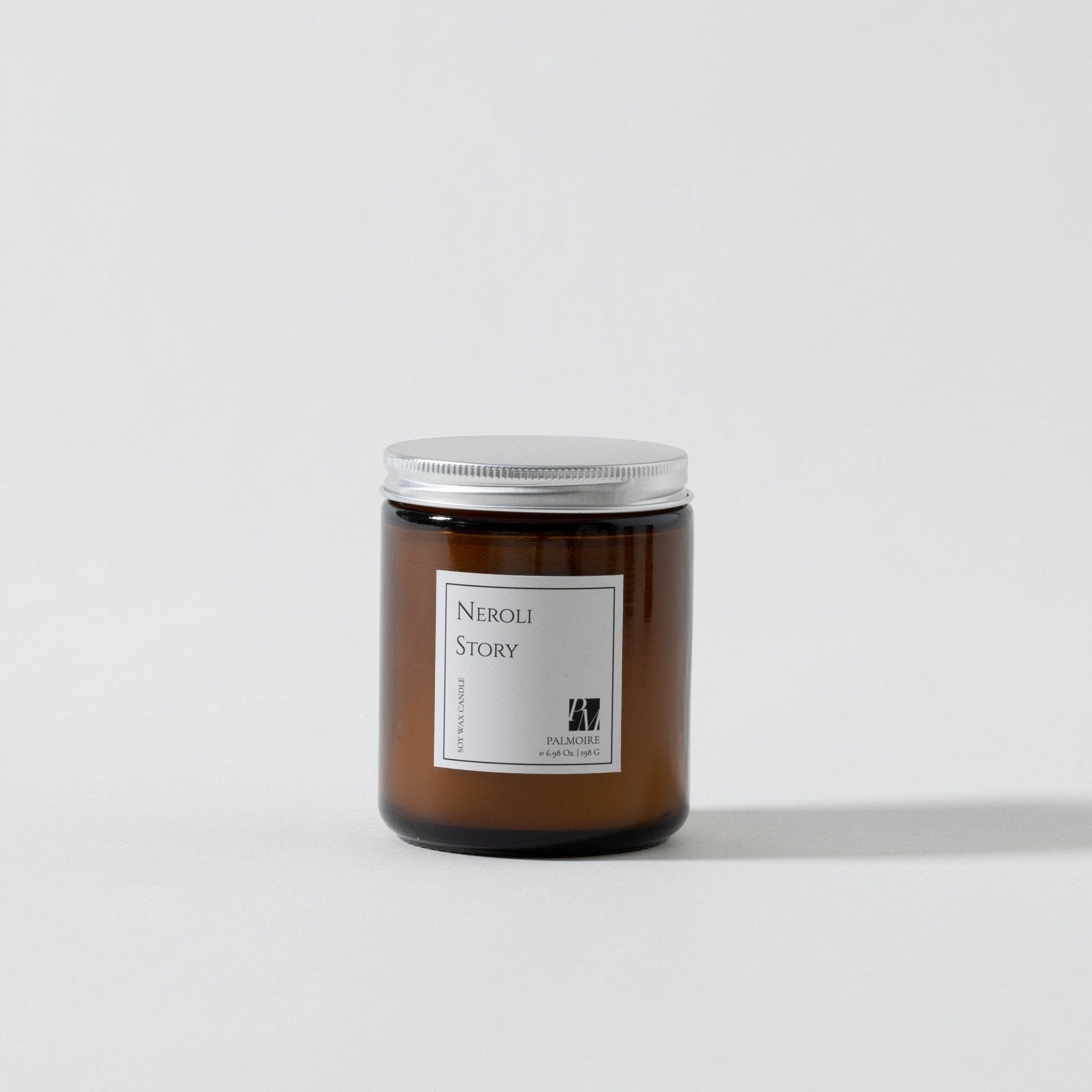 Brown glass soy wax candle with silver lid and white label reading Neroli Story.