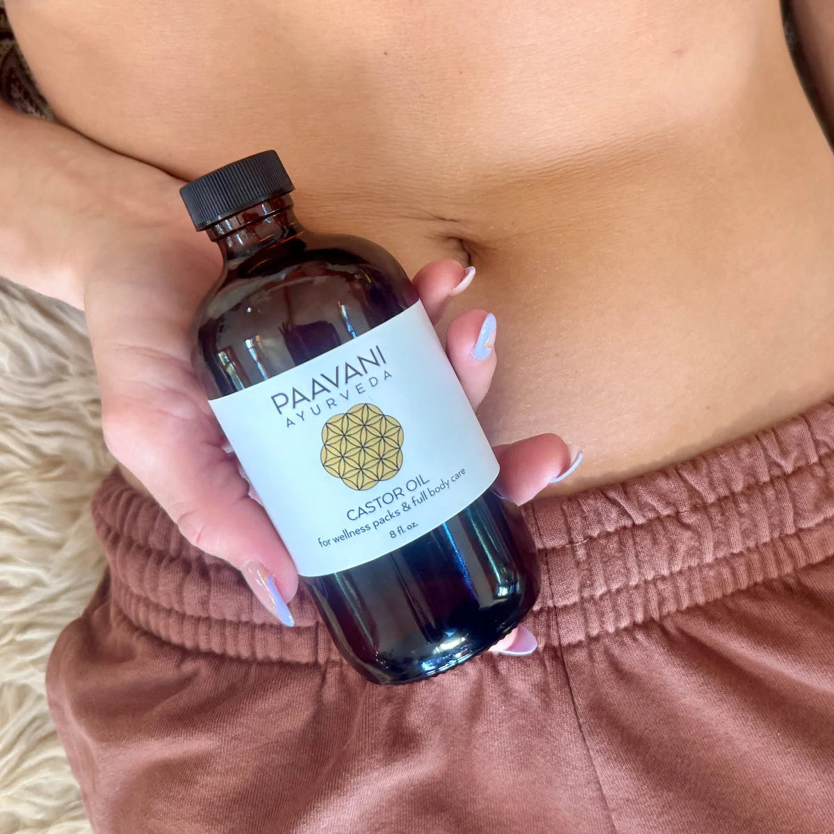 Paavani Ayurveda castor oil bottle held near the body