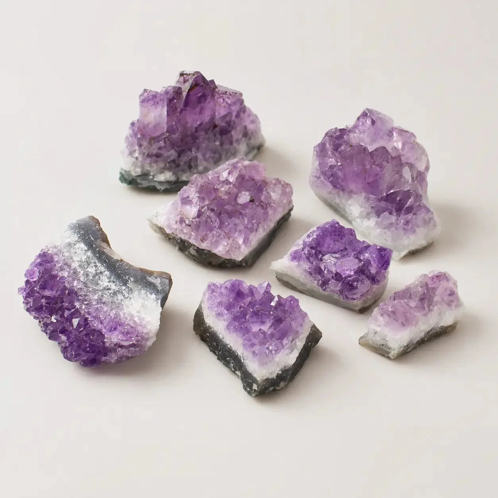 LumaStone New Arrival: Several raw amethyst crystal clusters in varying sizes, showcasing rich purple hues and natura...