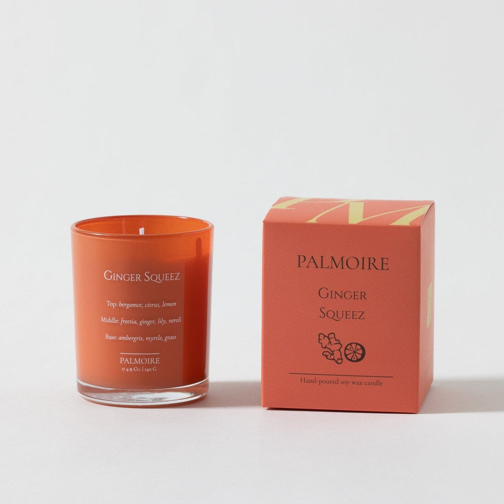 Orange glass soy wax candle labeled Ginger Squeez paired with matching orange box from Palmoire.
