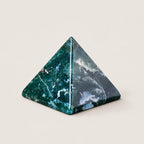 Polished moss agate pyramid crystal ornament on a warm ivory background