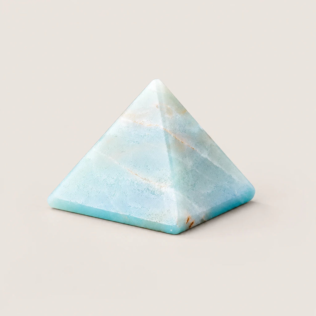 Polished amazonite pyramid crystal ornament on a warm ivory background