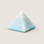 Polished amazonite pyramid crystal ornament on a warm ivory background