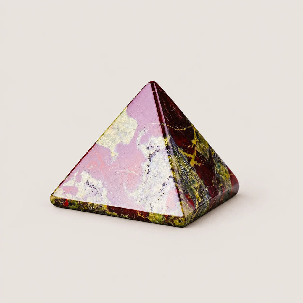 Polished dragon blood jasper pyramid crystal ornament on a warm ivory background