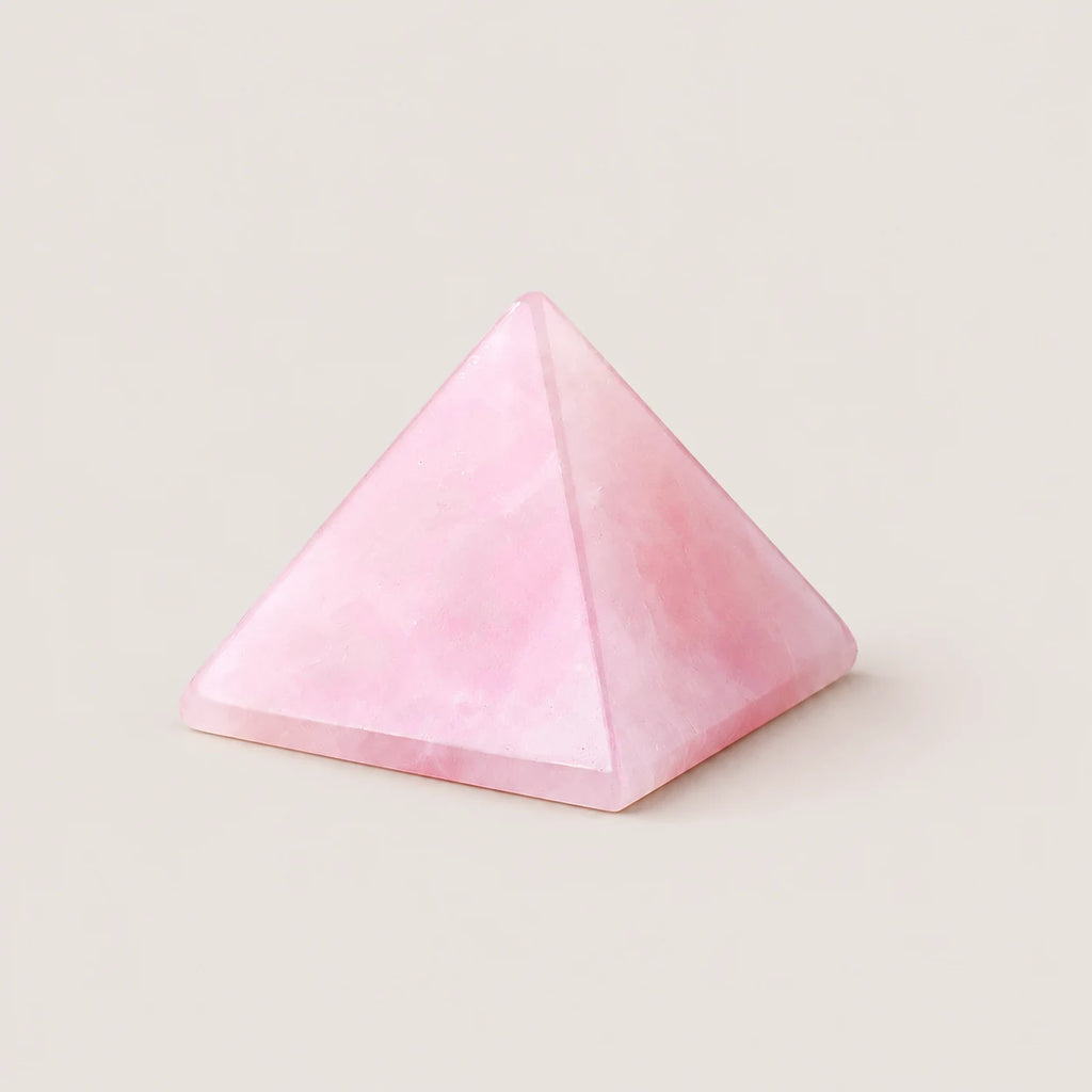Polished rose quartz pyramid crystal ornament on a warm ivory background