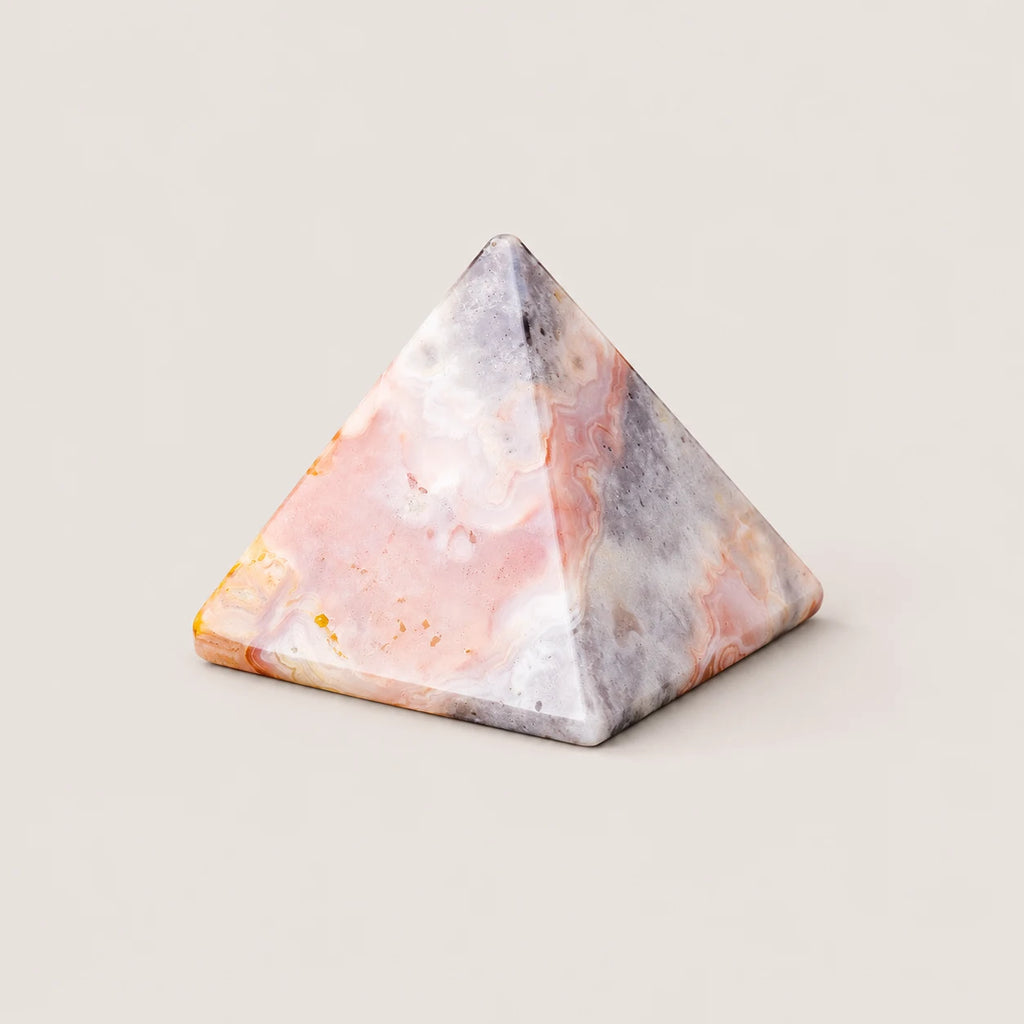 Polished agate pyramid crystal ornament on a warm ivory background