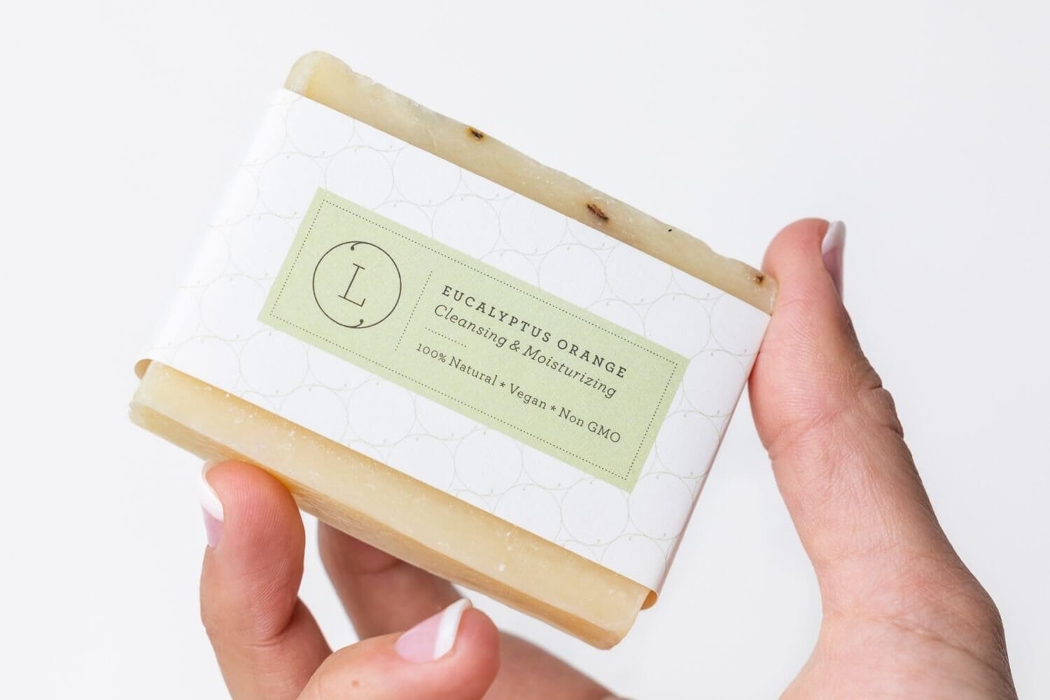 Handmade eucalyptus soap bar with green label and natural beige color held in hand.